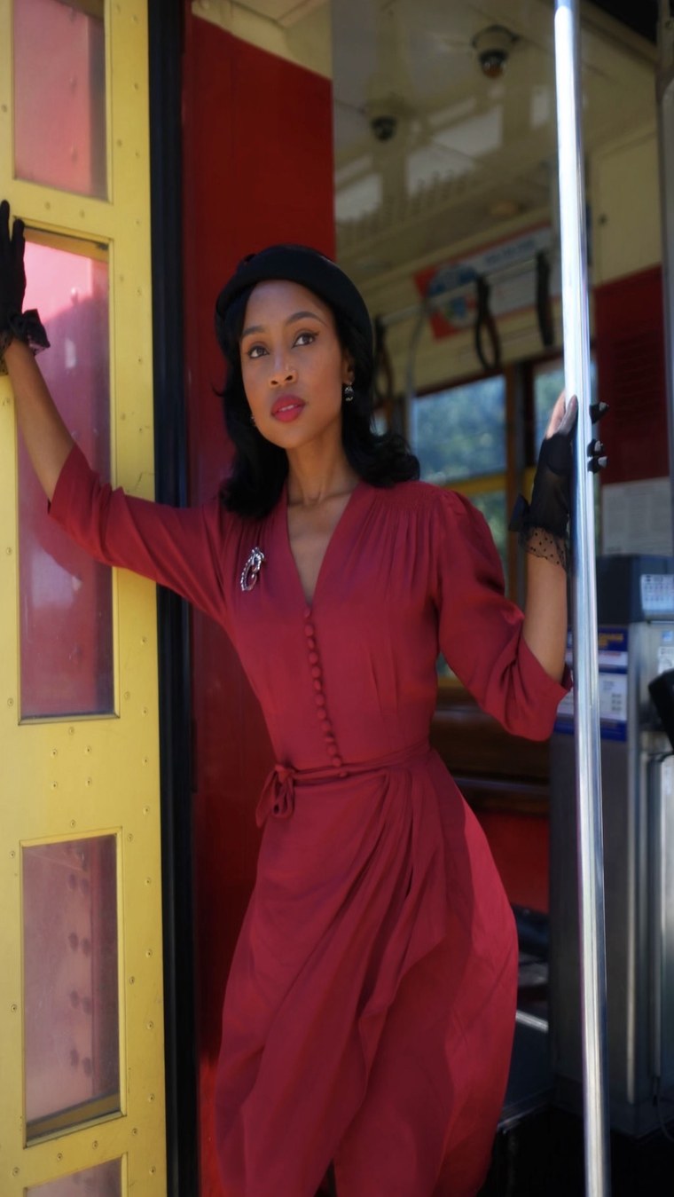 Red 1940s-style dress on a vintage streetcar
